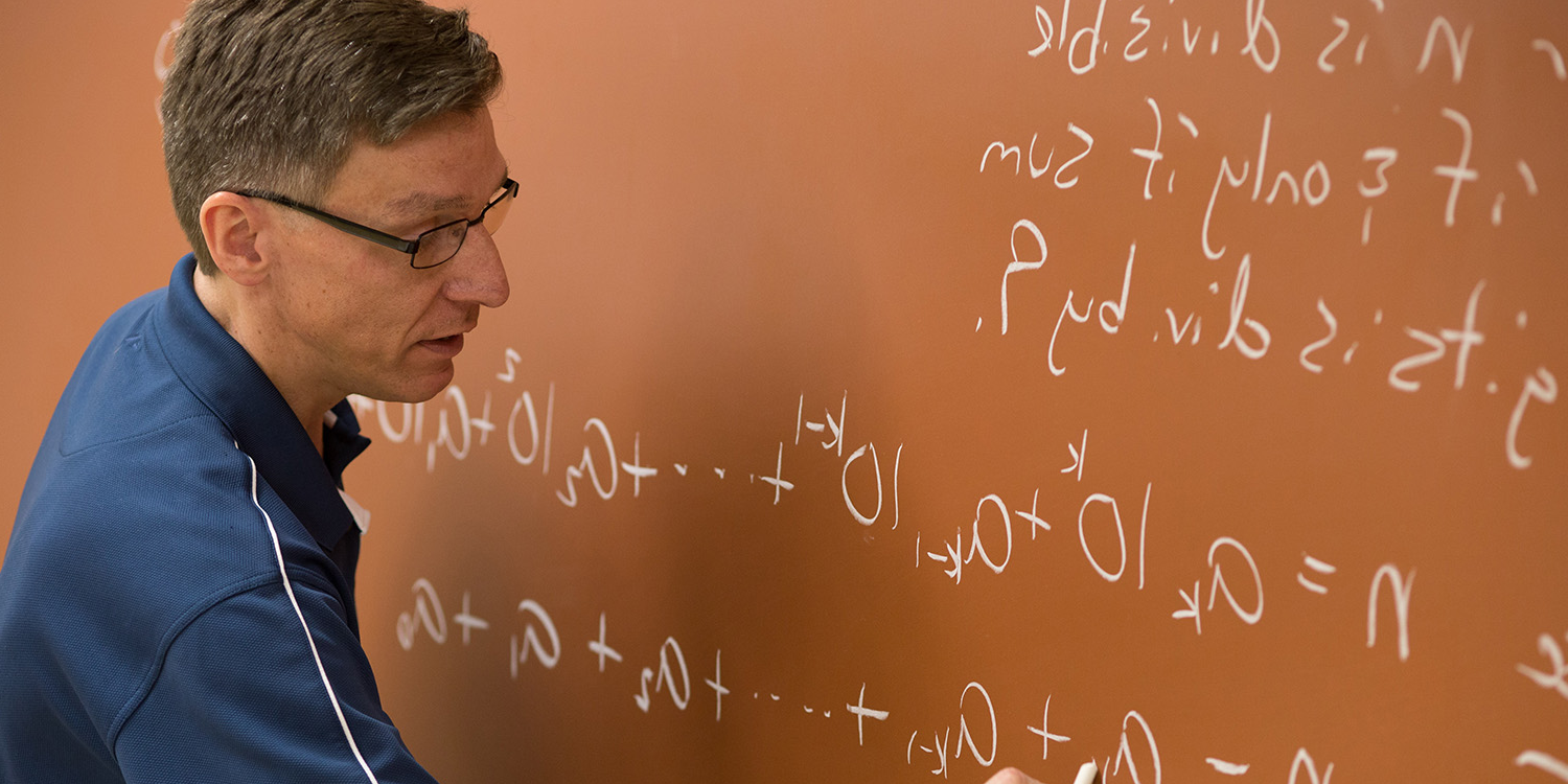 Math Professor Writing Formula On Chalkboard